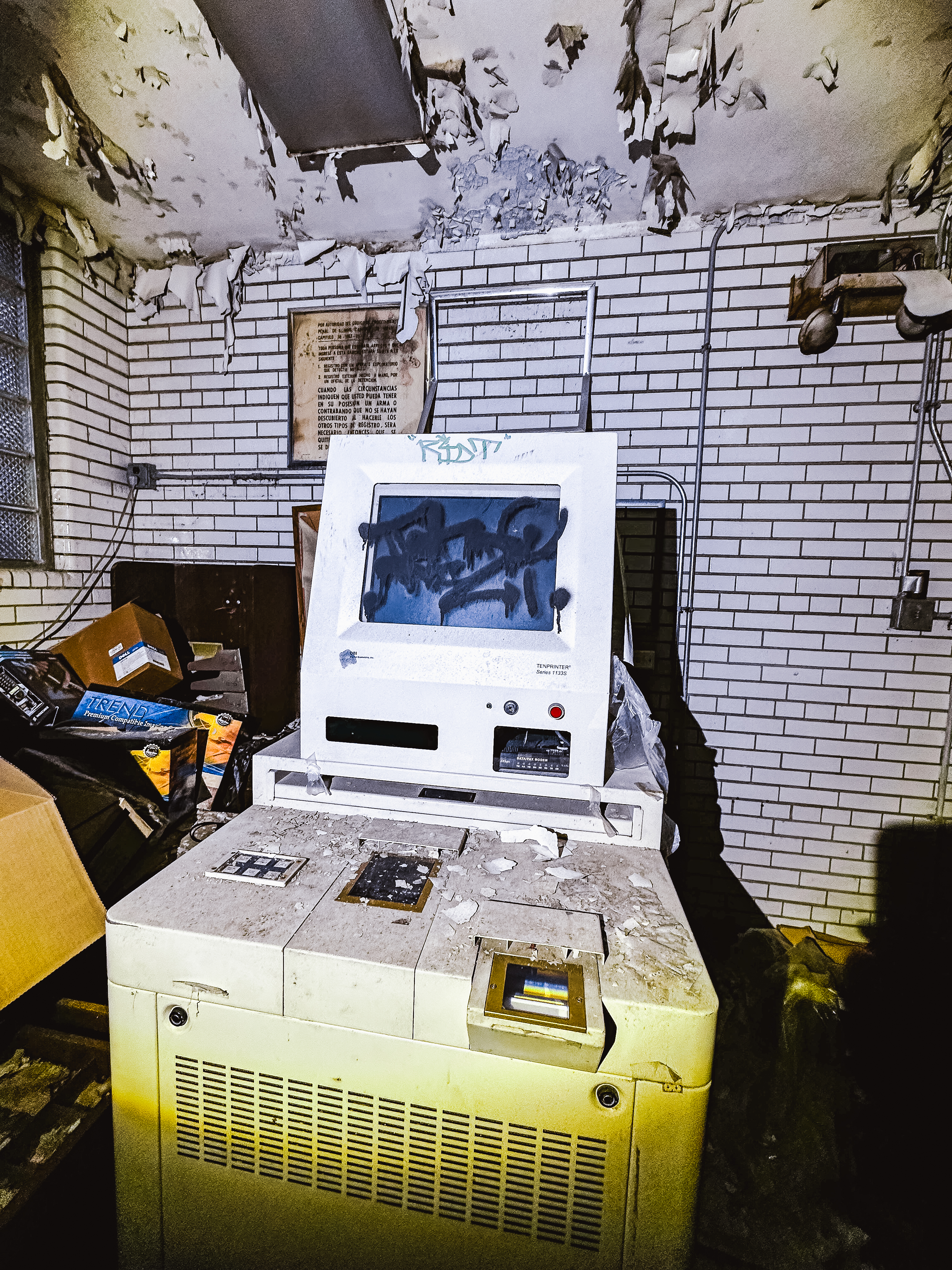 Old white computer covered in graffiti inside a police station room